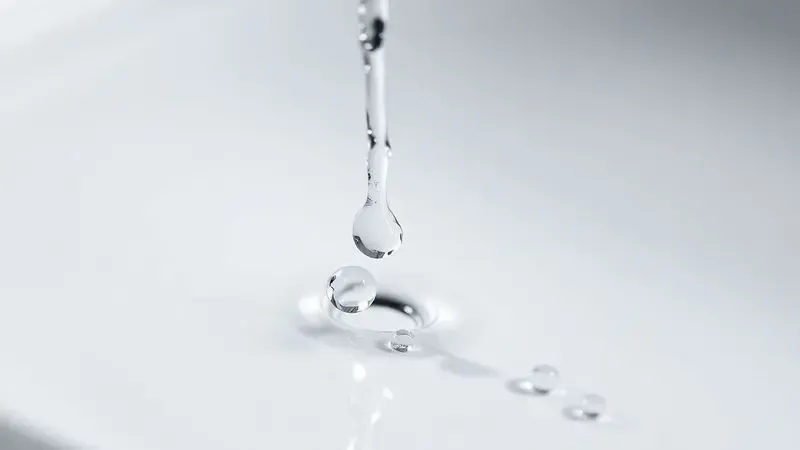 Representação artística de gotas de água deslizando em uma superfície cerâmica lisa, simbolizando facilidade de limpeza.