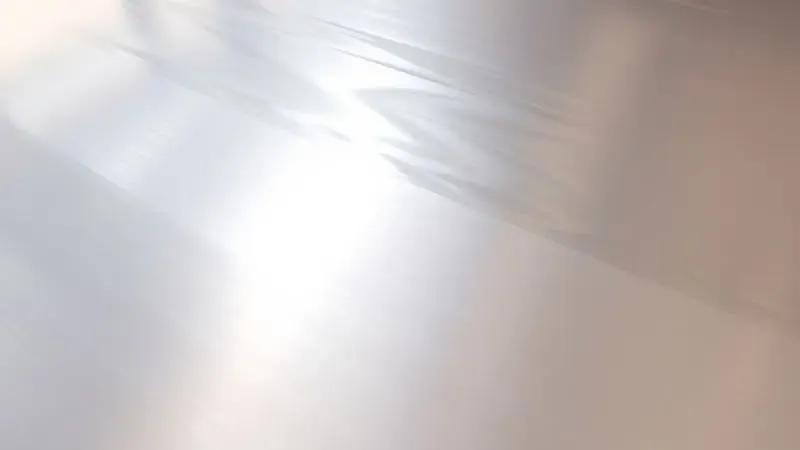 Renderização 3D de uma superfície de alumínio perfeitamente polida e reflexiva, capturando uma luz suave e quente.