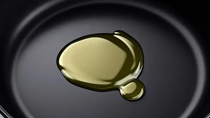Close na superfície de uma panela de ferro recebendo uma camada de óleo para o processo de curagem e proteção.
